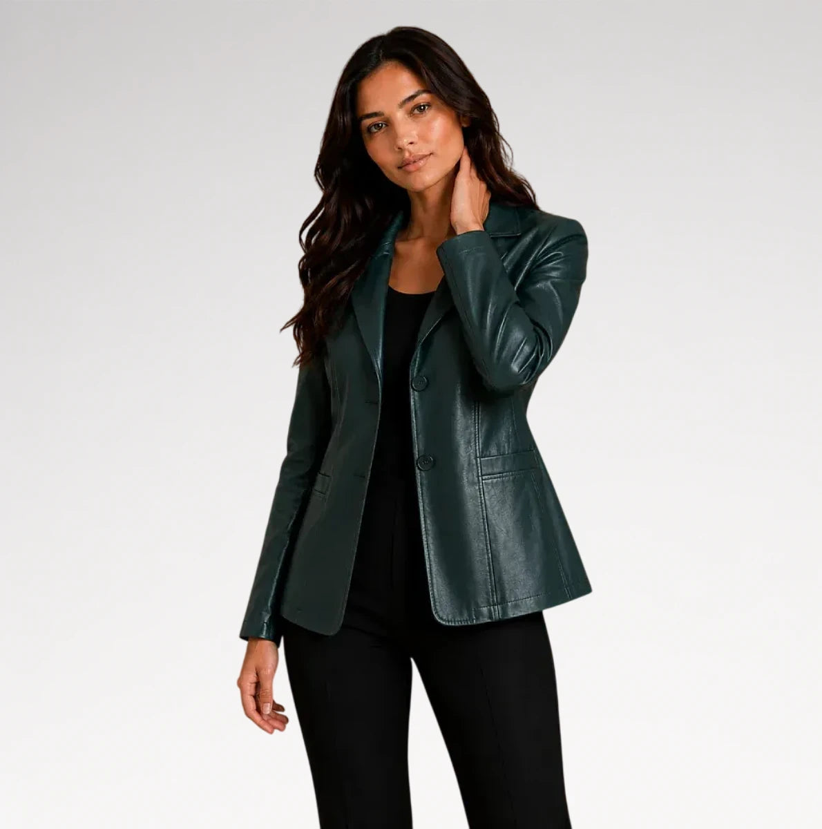 A woman modeling a dark green faux leather blazer over a black top and black pants, photographed against a light gray studio background.