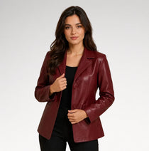A woman modeling a burgundy faux-leather blazer over a black top and black pants, photographed against a light gray studio background.
