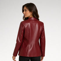 A woman wearing a fitted, long-sleeve burgundy faux-leather blazer, shown from a rear three-quarter view against a light gray studio background.