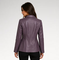 A woman shown from the back wearing a fitted, long-sleeve faux leather blazer in a muted plum purple color, paired with black pants, against a light gray studio background.