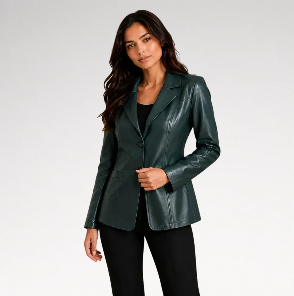 A woman modeling a dark green faux-leather blazer over a black top and black pants, photographed against a light gray studio background.