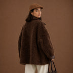 Woman wearing a brown textured coat and cap against a brown background