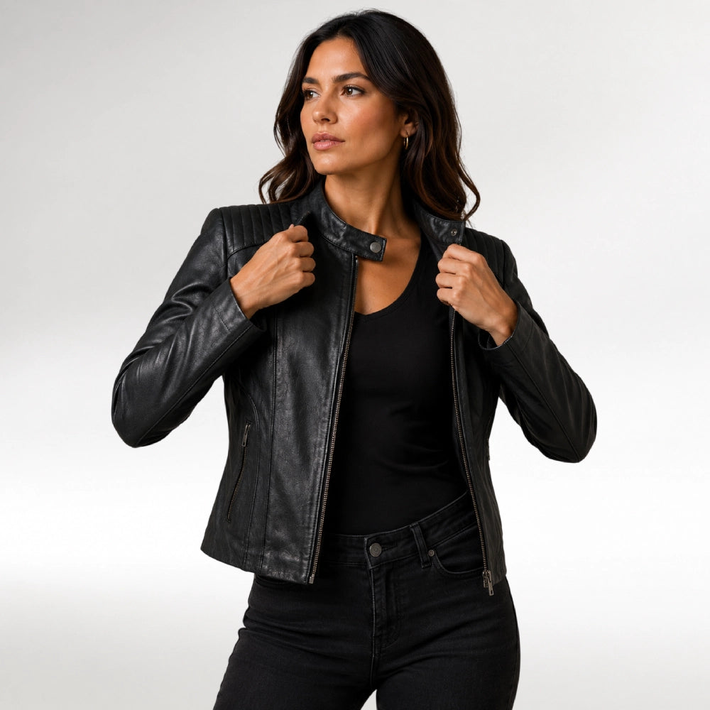 A woman modeling a black leather moto jacket over a black top and black jeans, posing against a light gray studio background. Main image