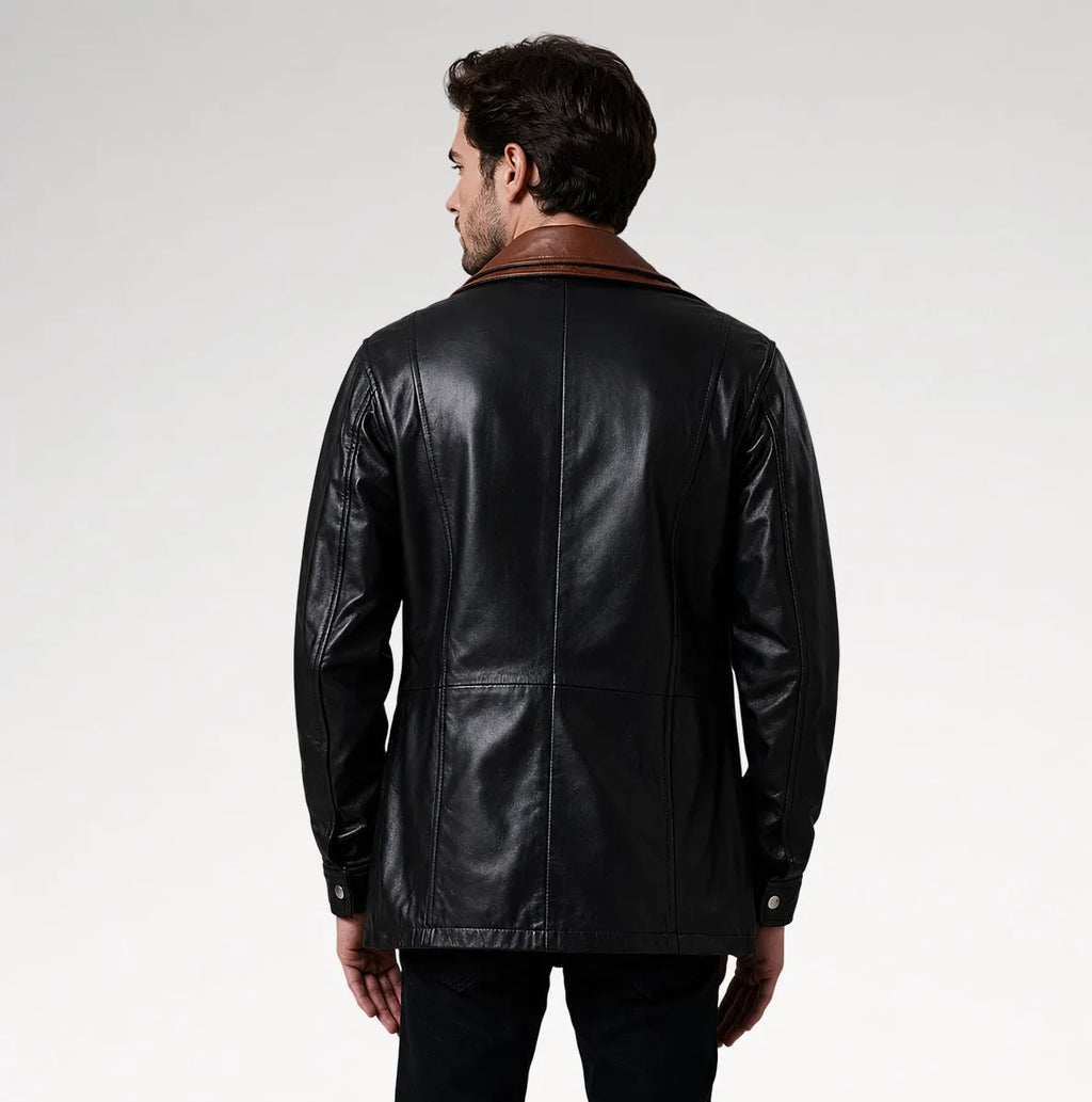 A man viewed from the back wearing a black leather jacket with a brown collar, set against a plain light gray studio background.