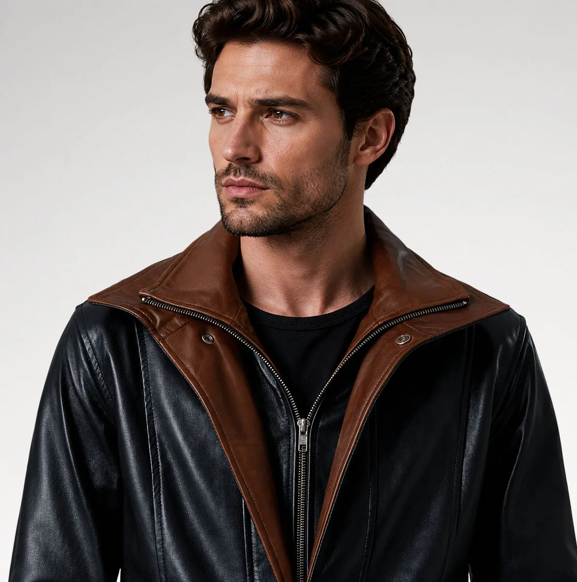 A man wearing a black leather jacket with a contrasting brown collar and zipper trim, photographed against a light gray studio background.