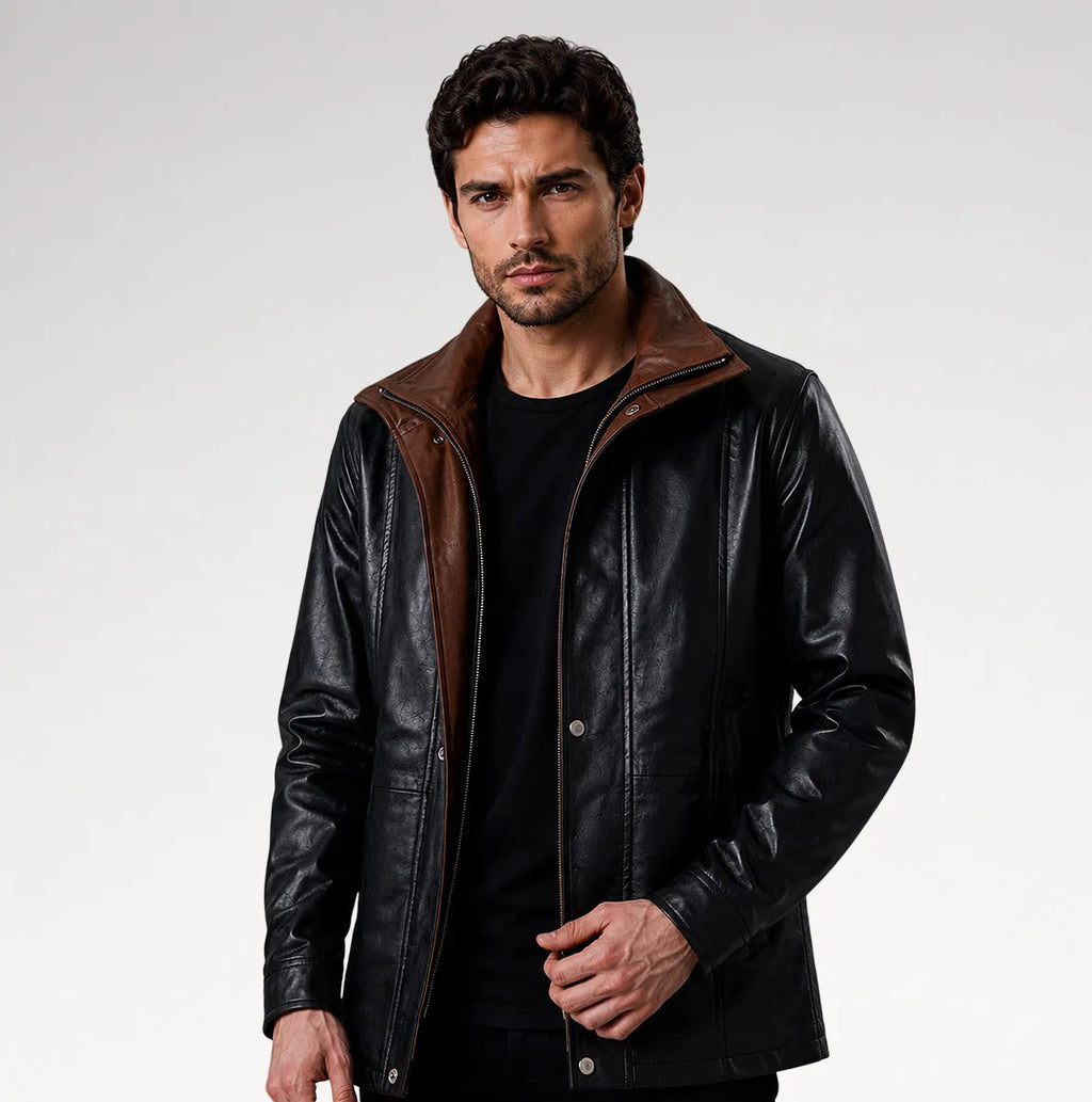 A man wearing a black leather jacket with brown faux-suede lining on the collar and zipper placket, styled over a black t-shirt against a light gray studio background.