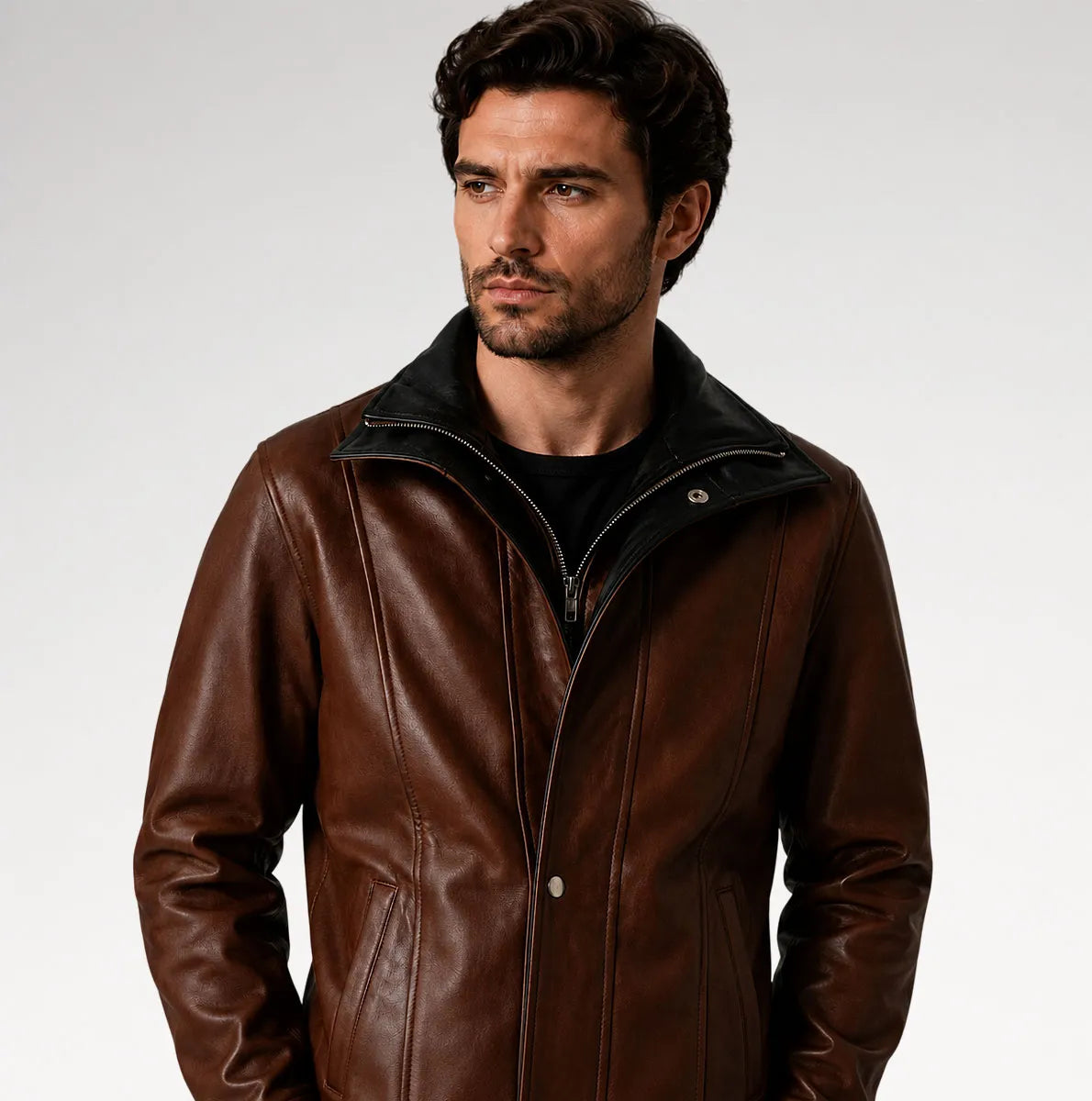 A man wearing a brown leather jacket with a black collar and zipper, photographed against a light gray studio background.
