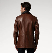 A man viewed from the back wearing a brown leather jacket with a black collar, set against a plain light gray studio background.