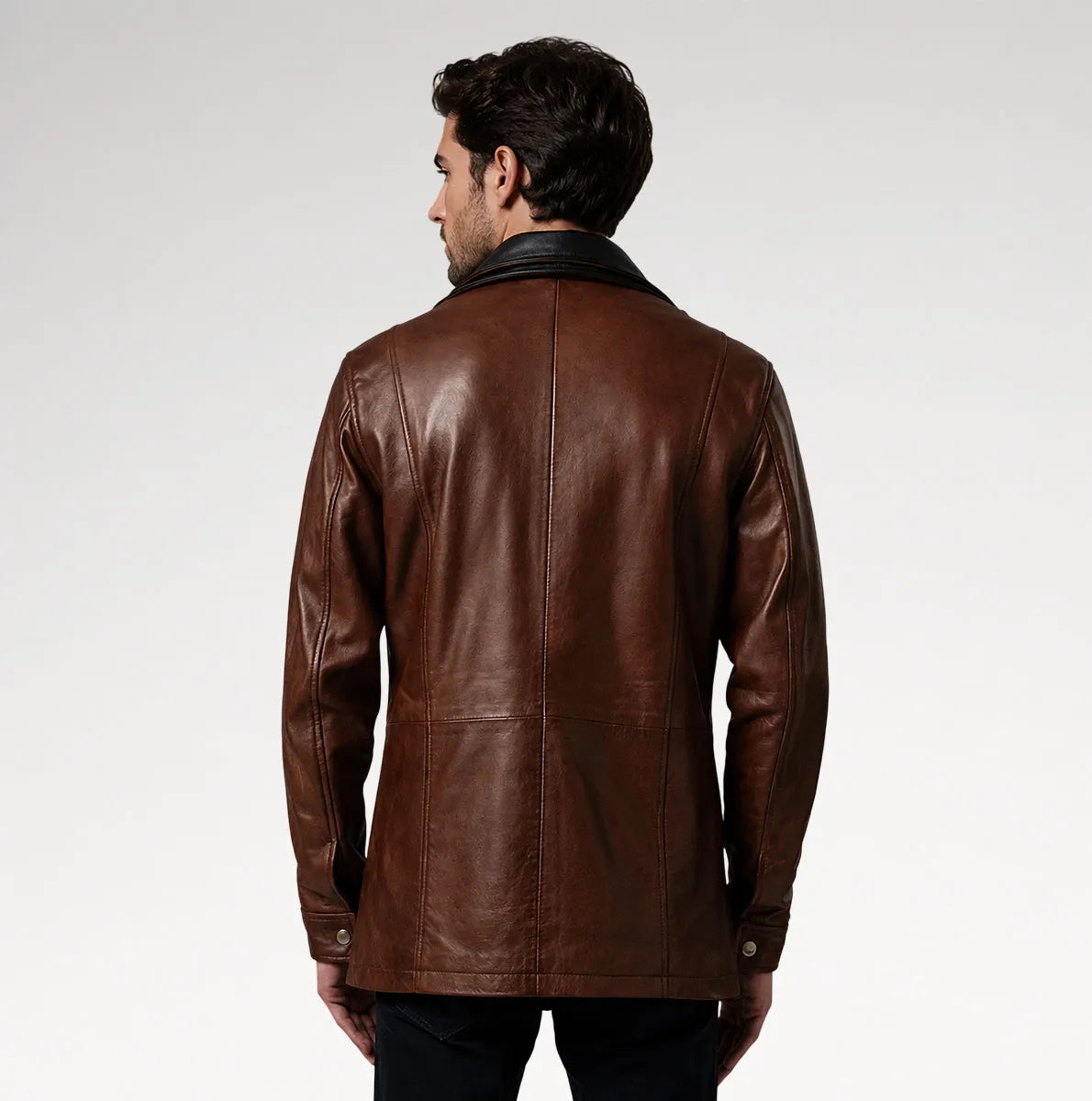 A man viewed from the back wearing a brown leather jacket with a black collar, set against a plain light gray studio background.