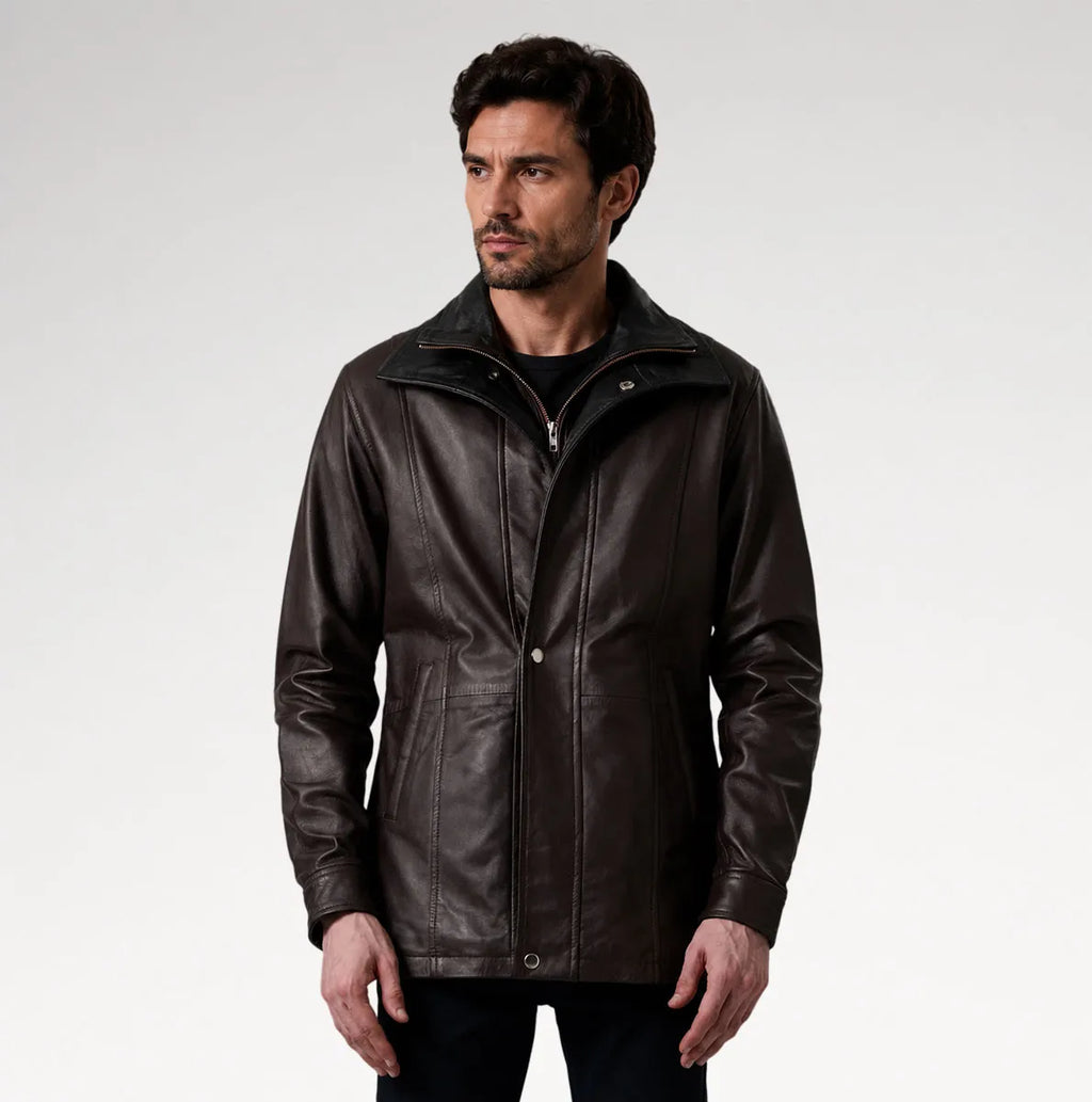 A man wearing a dark brown leather jacket with a high collar and front zipper, photographed against a light gray studio background.