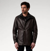 A man wearing a dark brown leather jacket with a high collar and front zipper, photographed against a light gray studio background.