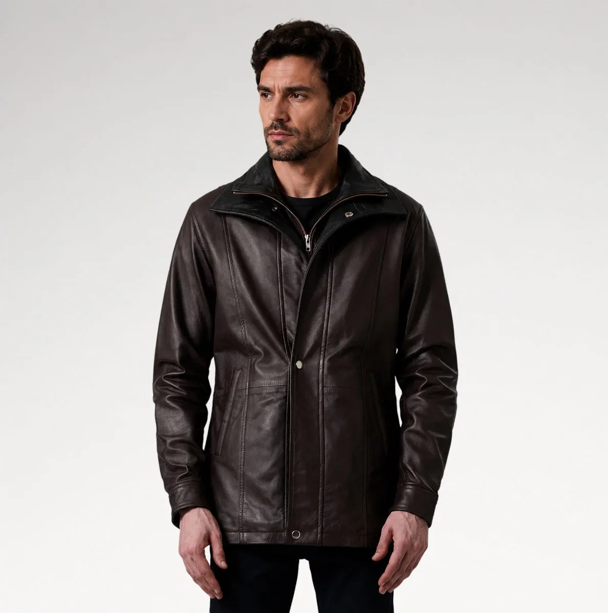 A man wearing a dark brown leather jacket with a high collar and front zipper, photographed against a light gray studio background.