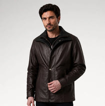 A man wearing a dark brown leather jacket with a high collar and front zipper, photographed against a light gray studio background.