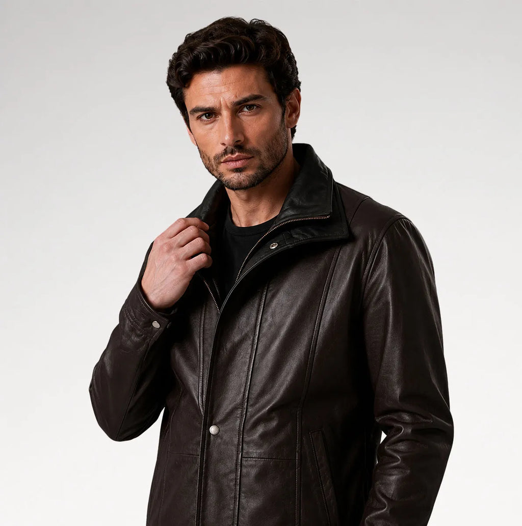 A man wearing a dark brown leather jacket over a black shirt, photographed against a light gray studio background.