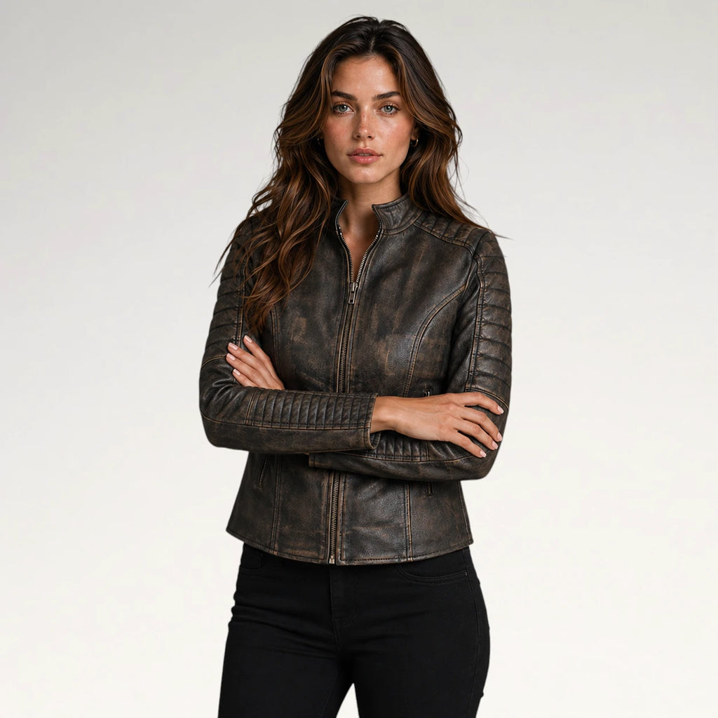 A woman modeling a dark brown distressed leather jacket with quilted shoulder panels and a front zipper, paired with black pants, against a light gray studio background.