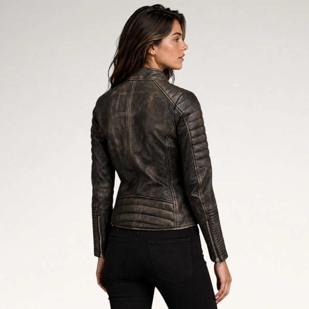 A woman shown from the back wearing a dark brown distressed leather jacket with quilted shoulder panels and zippered sleeves, paired with black pants, against a light gray studio background.