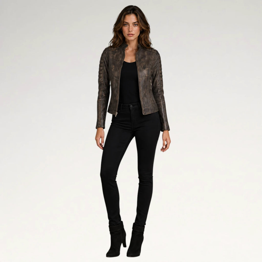 A woman modeling a dark brown textured leather jacket with a snakeskin pattern, worn over a black top and black skinny jeans, against a light gray studio background.