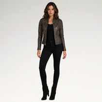 A woman modeling a dark brown textured leather jacket with a snakeskin pattern, worn over a black top and black skinny jeans, against a light gray studio background.