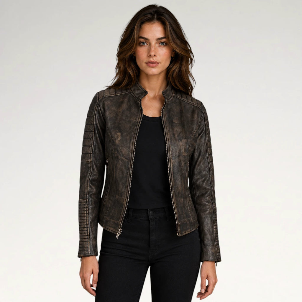 A woman modeling a distressed dark brown faux leather moto jacket with silver zippers, worn over a black top and black jeans, against a plain light gray background.
